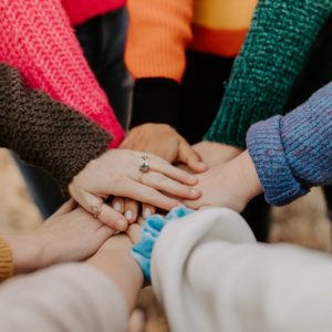 person in red sweater holding babys hand
